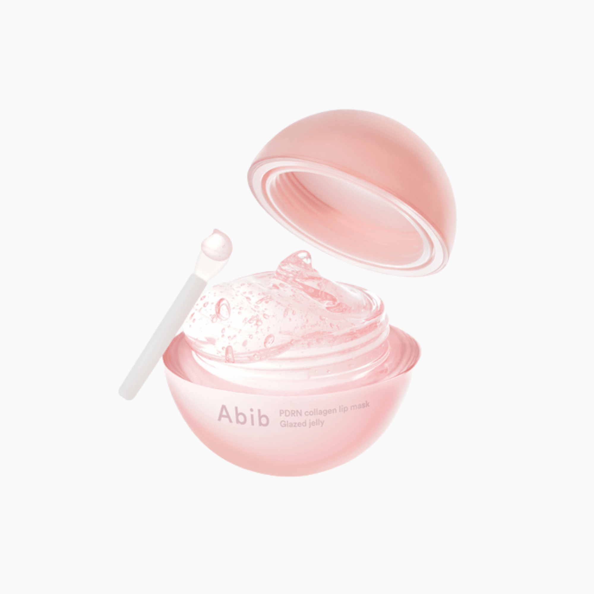 Ein geöffneter, rosafarbener, kugelförmiger Behälter der Abib PDRN Collagen Lip Mask zeigt ein klares Gel im Inneren, daneben liegt ein Applikator auf einer weißen Fläche.