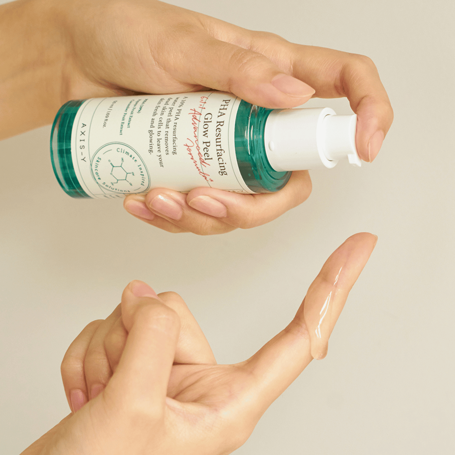Eine Hand pumpt eine kleine Menge des Axis-Y Glow Peels auf den Finger – klare Geltextur sichtbar vor beigem Hintergrund 