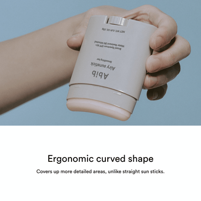 Eine Hand hält einen beigefarbenen, ergonomischen Abib Airy Sunstick Smoothing Bar 23g, dessen Design und Deckkraft unten angezeigt wird.