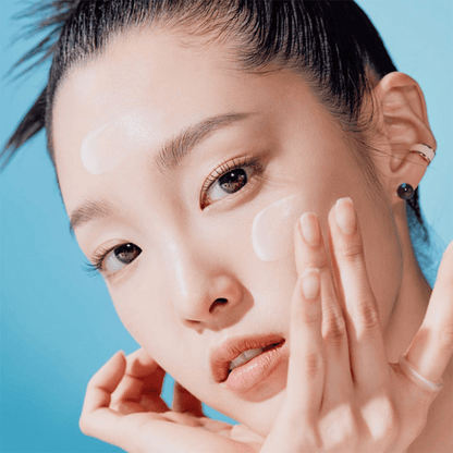 Frau trägt die Tocobo Bio Watery Sun Cream mit SPF50+ sanft auf Stirn und Wangen auf koreanische Gesichtspflege