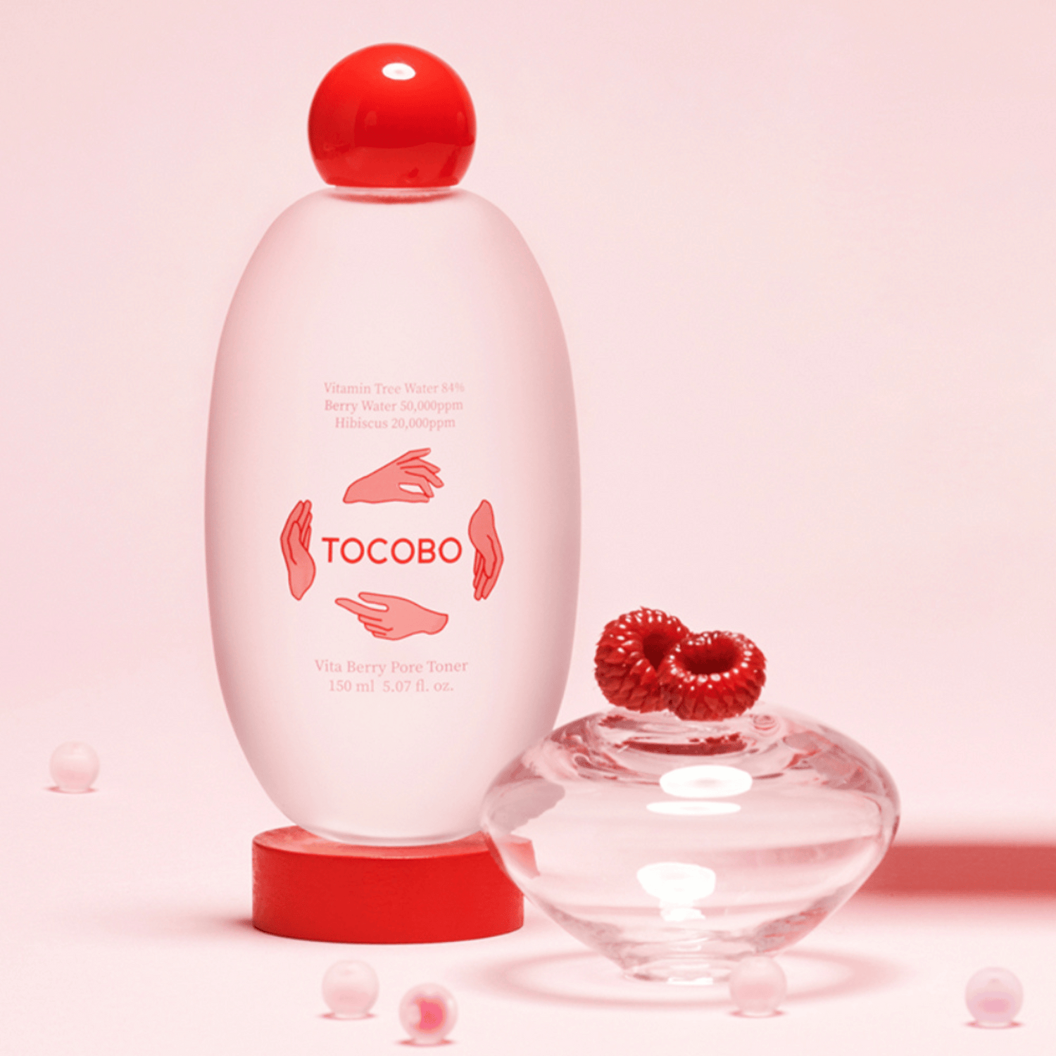 Inszeniertes Produktbild des Tocobo Vita Berry Pore Toners mit Himbeere und dekorativen Glaselementen auf rosa Fläche 