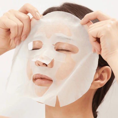 Frau legt die VT Cica Collagen Mask auf ihr Gesicht auf, pflegende Sheetmaske mit Collagen für Elastizität und Feuchtigkeit