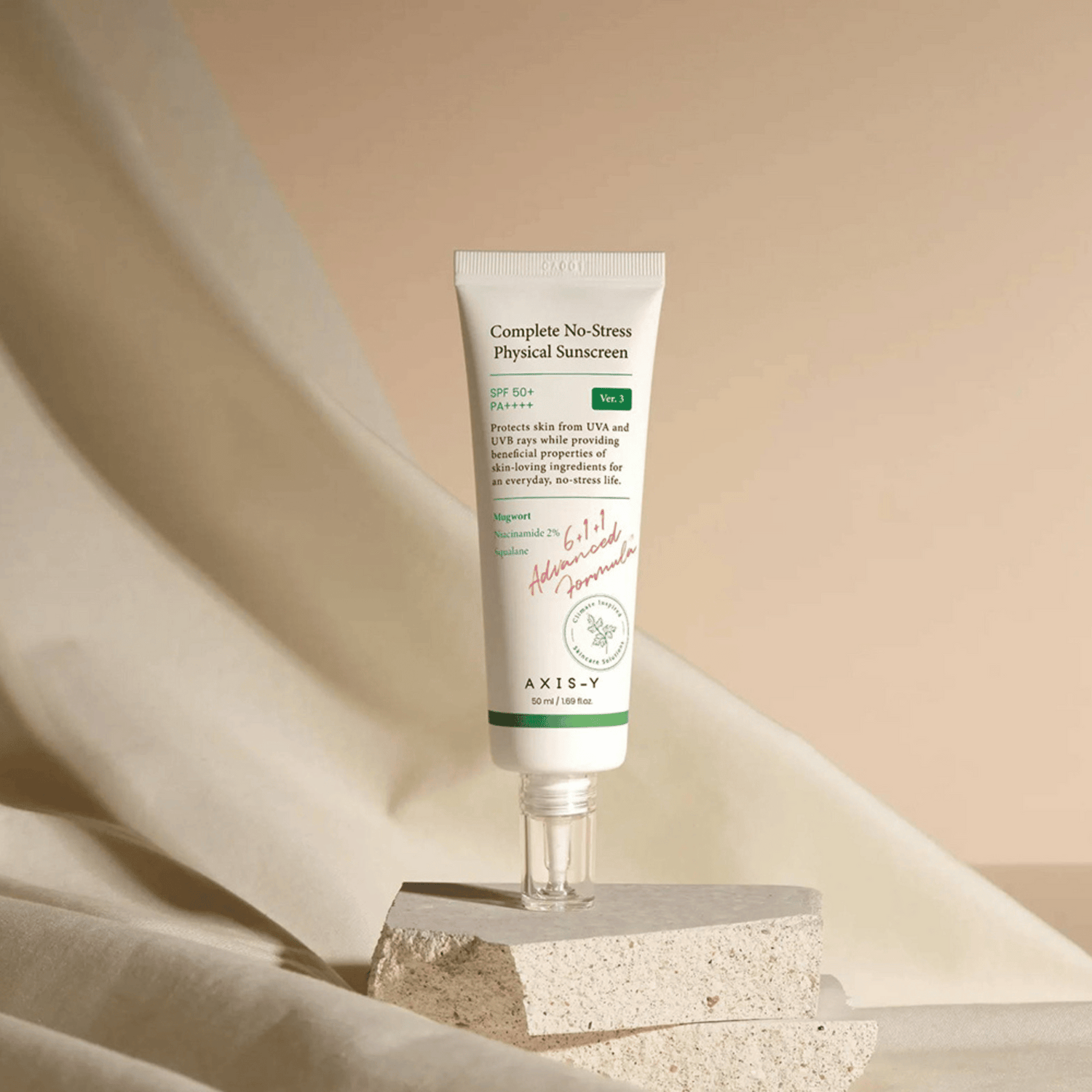 AXIS-Y Complete No-Stress Physical Sunscreen mit SPF 50+ auf strukturiertem Untergrund vor beigem Stoff im Hintergrund