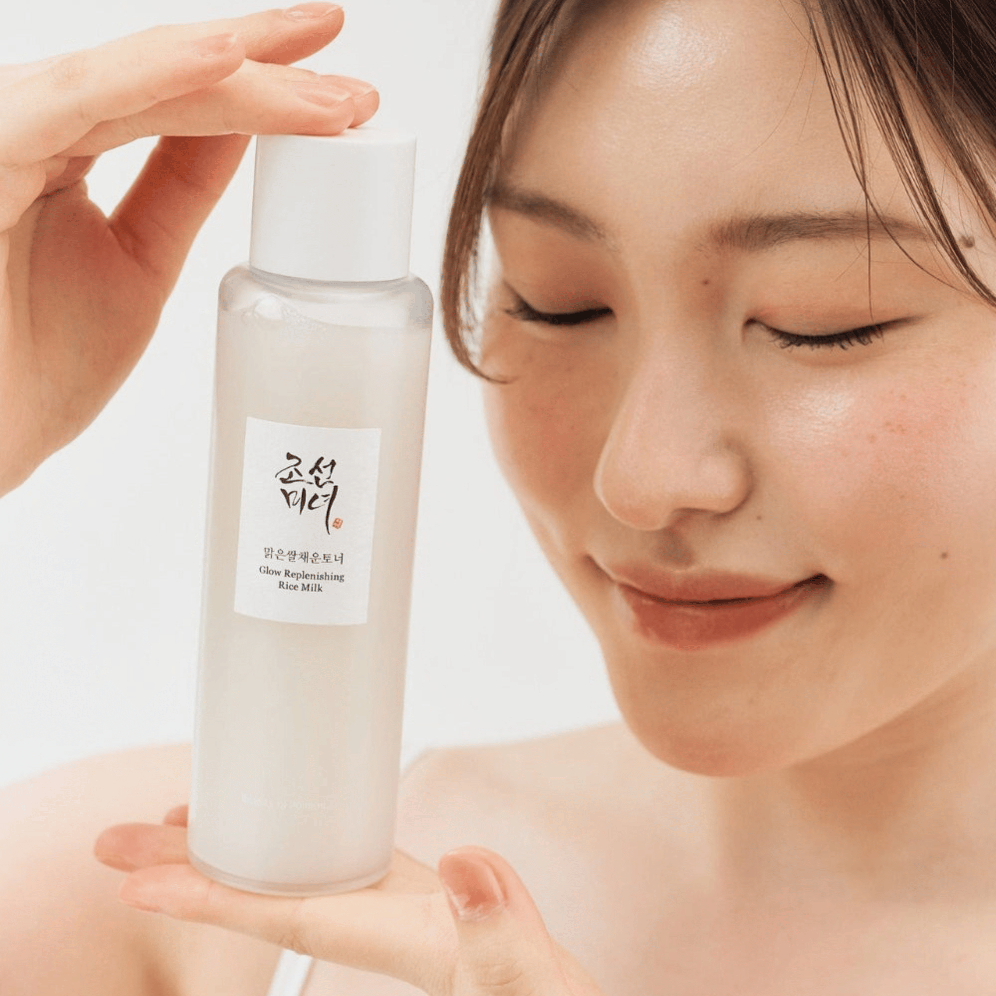 Frau mit geschlossenen Augen hält das Glow Replenishing Rice Milk aus der korean skincare Linie von Beauty of Joseon