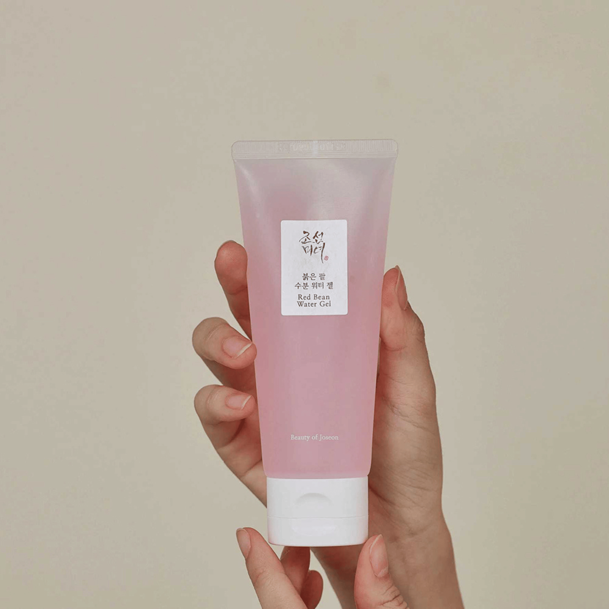 Beauty of Joseon Red Bean Water Gel mit rosa Geltextur in transparenter Tube, fest in der Hand gehalten