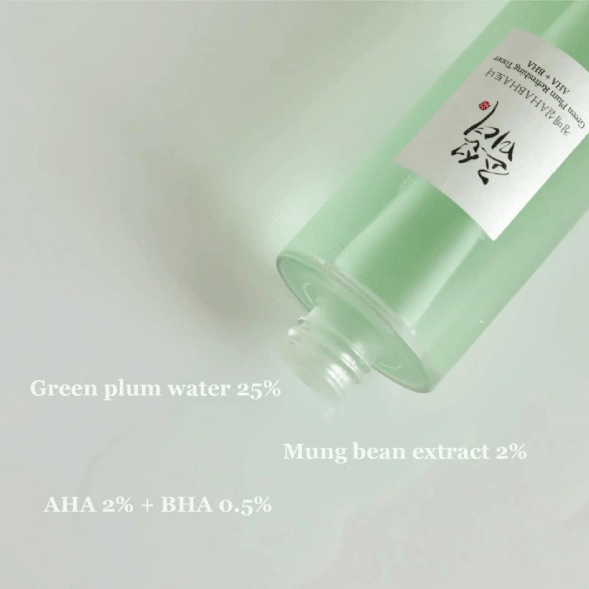 Grünlicher Toner mit 25 % Green Plum Water und AHA + BHA auf einer glatten Oberfläche verteilt