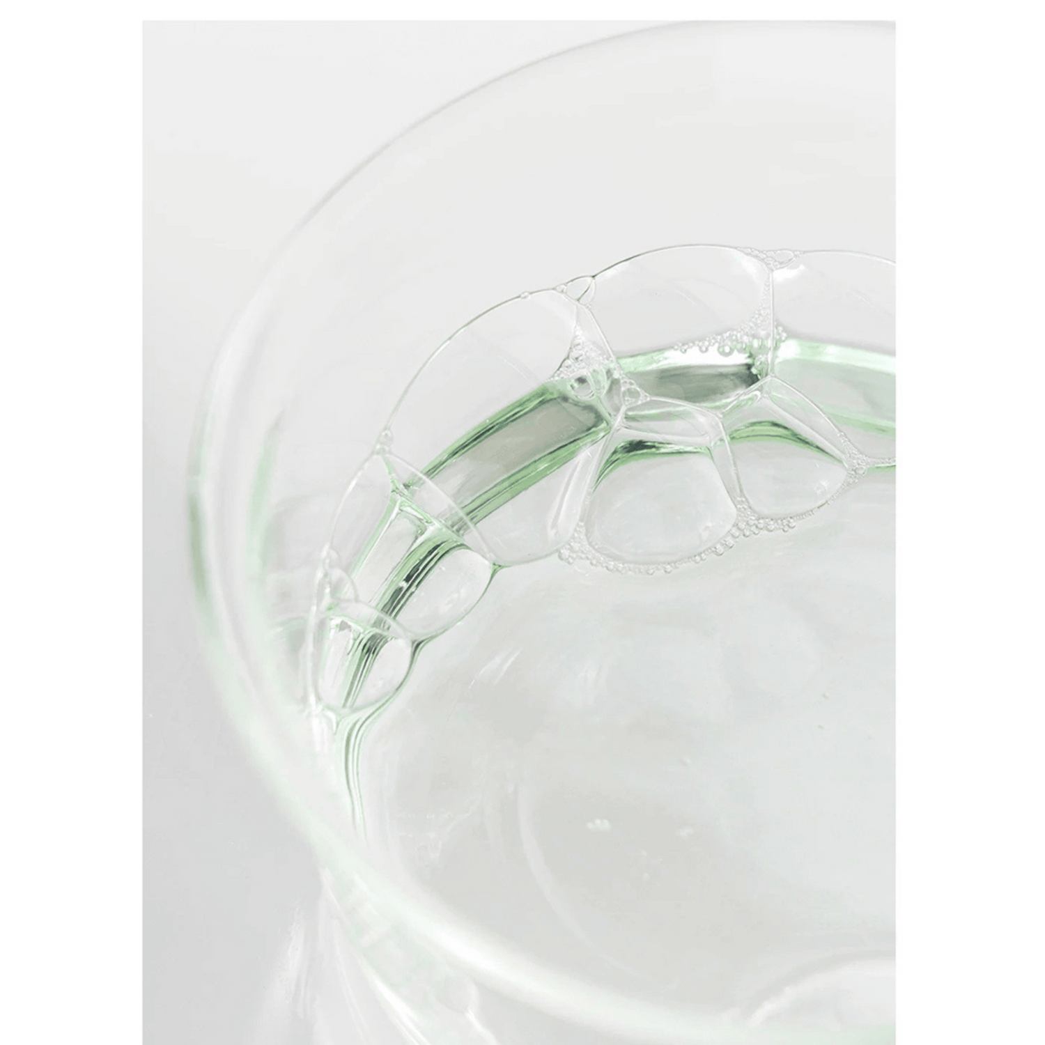 Klare, grünliche Flüssigkeit mit Schaumblasen in einer Glas-Petrischale – Textur des Toners von Beauty of Joseon