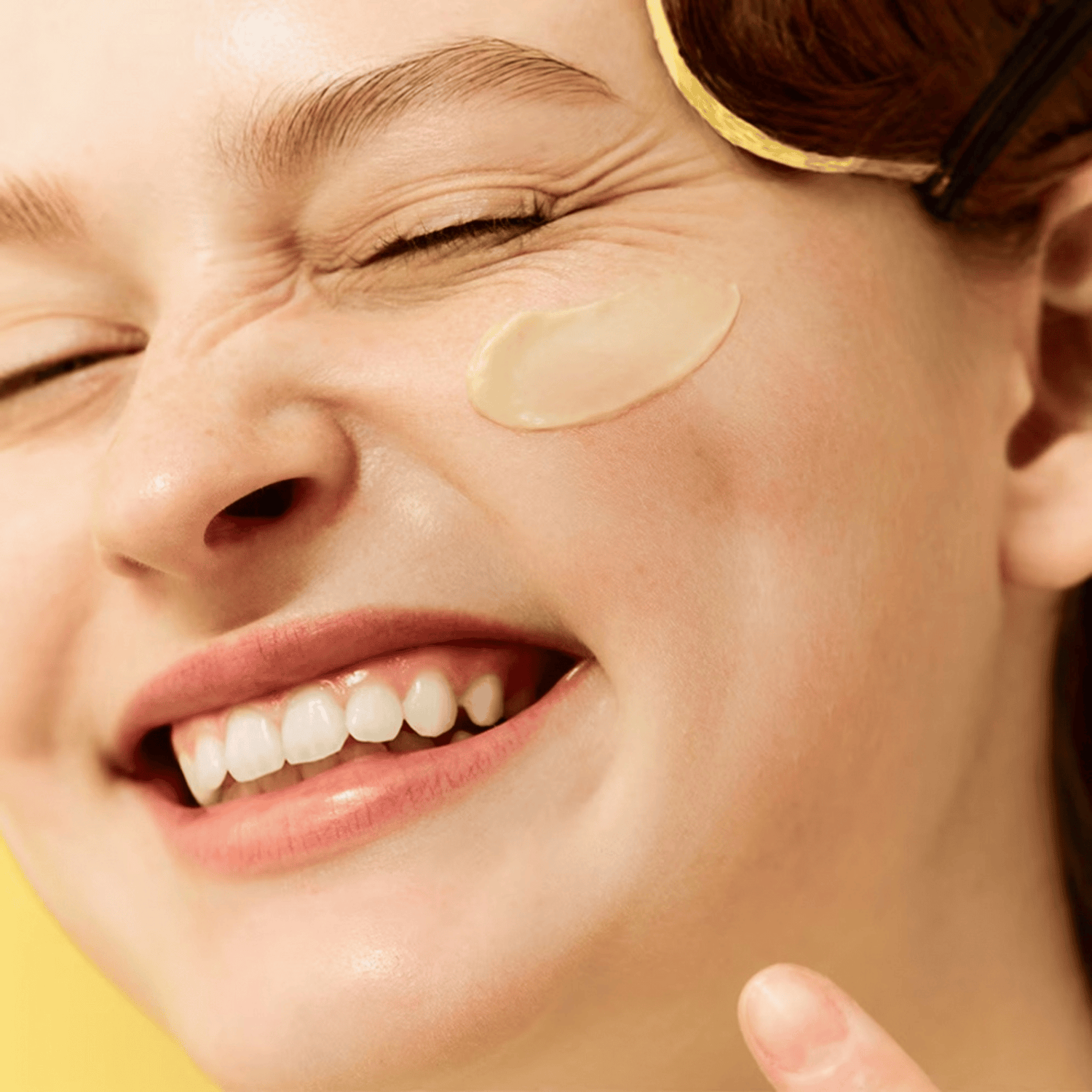 Eine Person lächelt mit geschlossenen Augen und trägt mit dem Finger Dr. Jart+ Ceramidin Skin Barrier Moisturizing Cream auf ihre Wange auf.